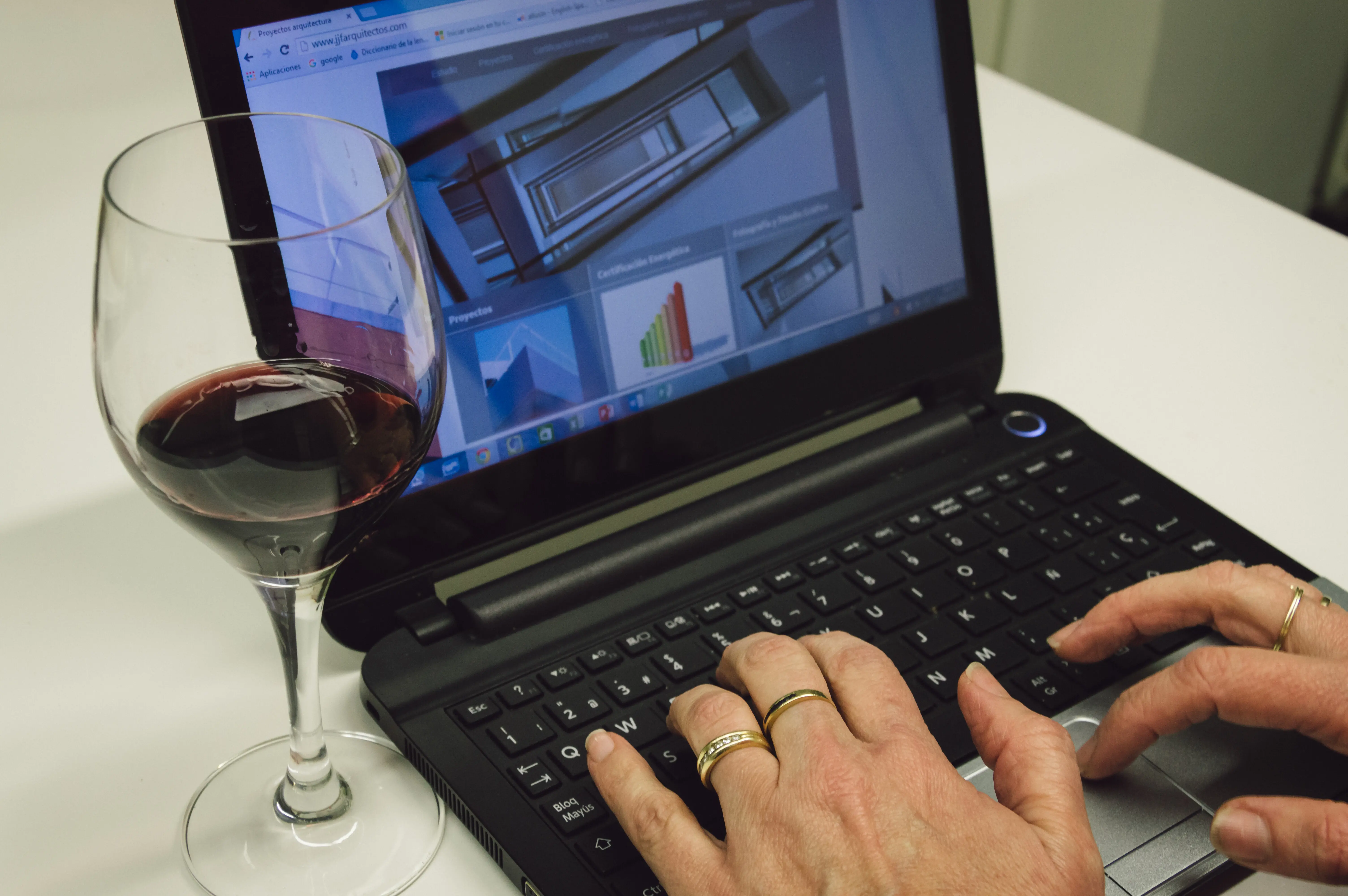 Zugeschnittenes Bild einer Frau, die zu Hause am Tisch einen Laptop benutzt.